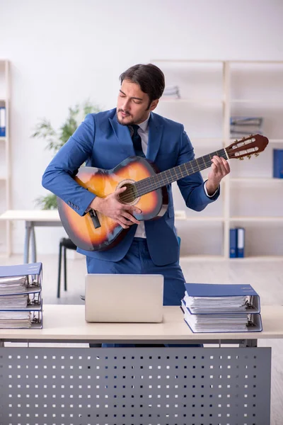 Jeune employé masculin jouant de la guitare sur le lieu de travail — Photo