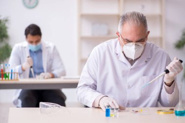 Salgın sırasında laboratuvarda çalışan iki erkek kimyager.