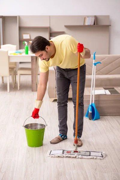 Jovem empreiteiro limpando a casa — Fotografia de Stock