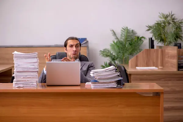 Junge männliche Mitarbeiter und zu viel Arbeit im Büro — Stockfoto