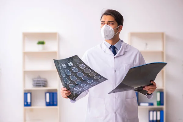 Jonge mannelijke arts radioloog werkzaam in de kliniek tijdens pande — Stockfoto
