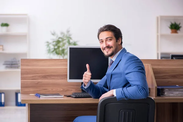 Empleado joven sentado en el lugar de trabajo — Foto de Stock