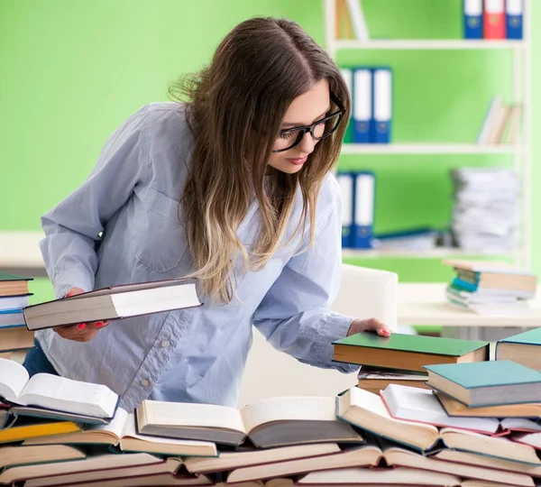 Jovem estudante se preparando para exames com muitos livros — Fotografia de Stock