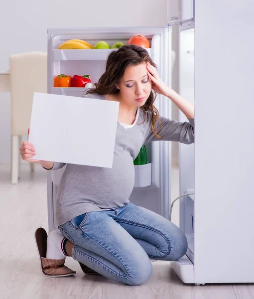 Mujer embarazada cerca de la nevera con mensaje en blanco —  Fotos de Stock