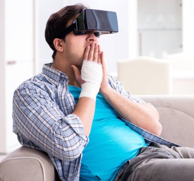 Eli yaralı bir adam sanal gerçeklik gözlüğü takıyor.