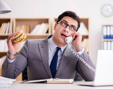 Aç komik iş adamı abur cubur sandviç yiyor.