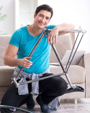 Evde bisiklet tamir eden genç bir adam.