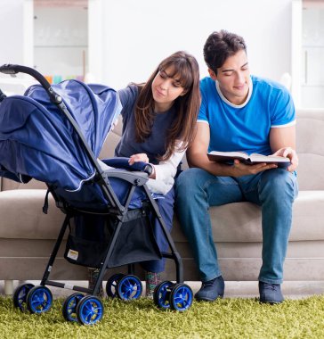 Bebekleri bebek arabasında oturan genç ebeveynler.