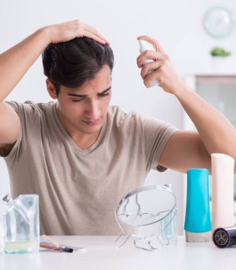 Genç yakışıklı adam aynaya bakıyor.