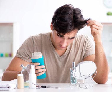 Genç yakışıklı adam aynaya bakıyor.