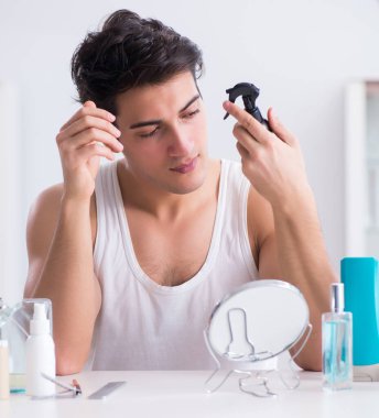 Genç yakışıklı adam aynaya bakıyor.