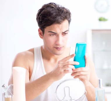 Genç yakışıklı adam aynaya bakıyor.