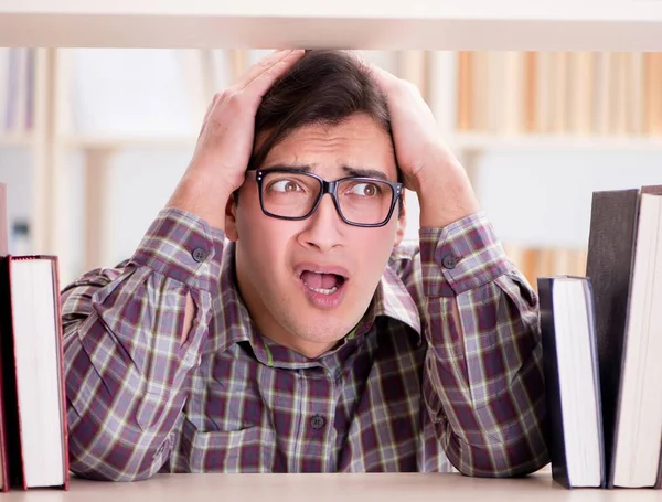 Giovane studente in cerca di libri nella biblioteca del college — Foto Stock