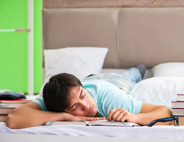 Студент готовился к экзаменам дома, в спальне, лежа на кровати — стоковое фото
