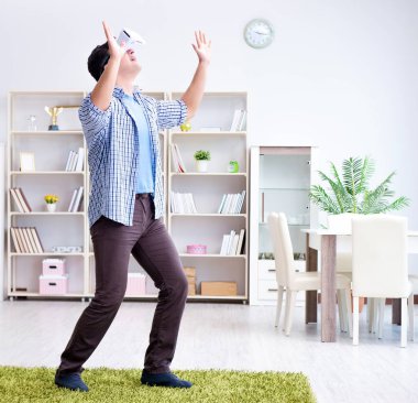 Evde sanal gerçeklik gözlüklü bir adam oynuyor.