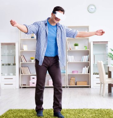 Evde sanal gerçeklik gözlüklü bir adam oynuyor.