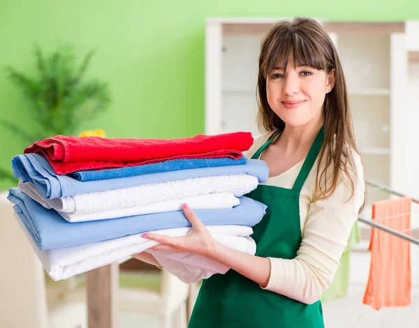 Jeune femme repassage vêtements à la maison — Photo