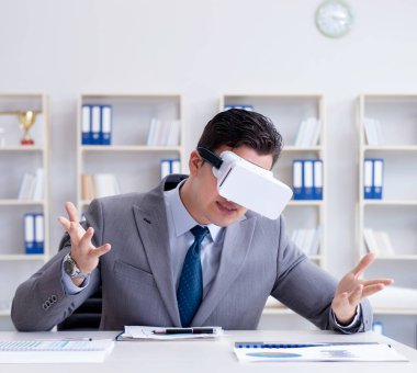 Ofiste sanal gerçeklik gözlüklü bir iş adamı var.