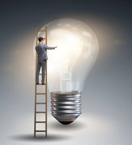 Businessman on ladder with light bulb — Stock Photo, Image