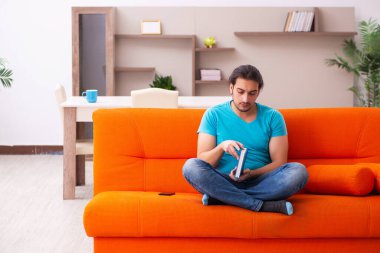 Genç erkek öğrenci turuncu koltukta oturuyor.