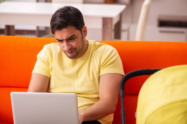 Genç adam evde yeni doğan çocuğa bakıyor.