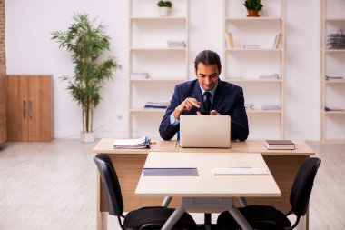 Genç erkek işveren ofiste oturuyor.