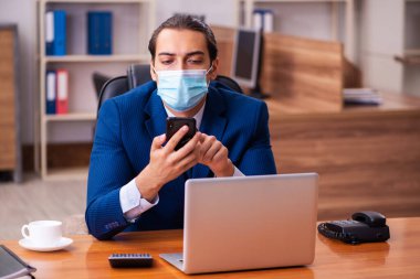 Ofiste maske takan genç bir erkek çalışan.