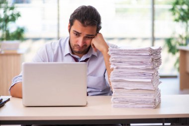 Ofisteki aşırı işten memnun olmayan genç bir erkek işçi.