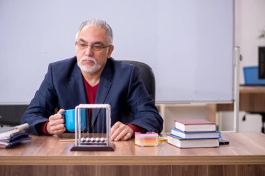 Sınıfta oturan eski bir fizikçi öğretmen.