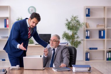 Ofiste zorbalık konseptiyle çalışan iki erkek çalışan.