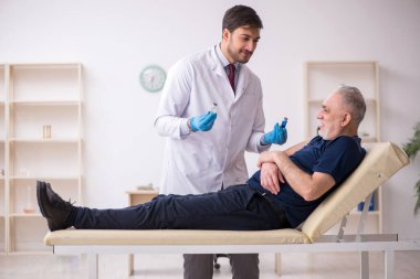 Yaşlı bir erkek hasta aşıyla genç bir doktoru ziyaret ediyor.