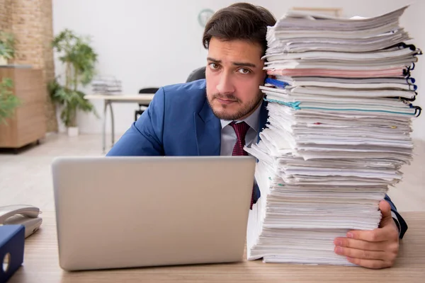 Ung manlig anställd och för mycket arbete på kontoret — Stockfoto