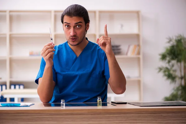 Молодий лікар тримає шприц у клініці — стокове фото
