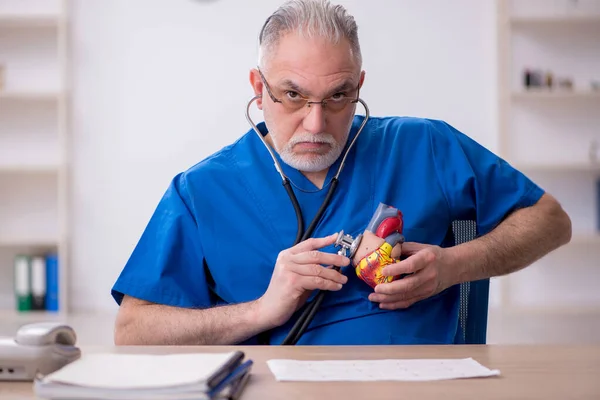 クリニックで働いている古い男性医師心臓病学者 — ストック写真