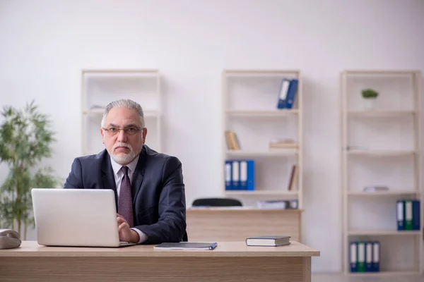 Alte männliche Mitarbeiter sitzen am Arbeitsplatz — Stockfoto