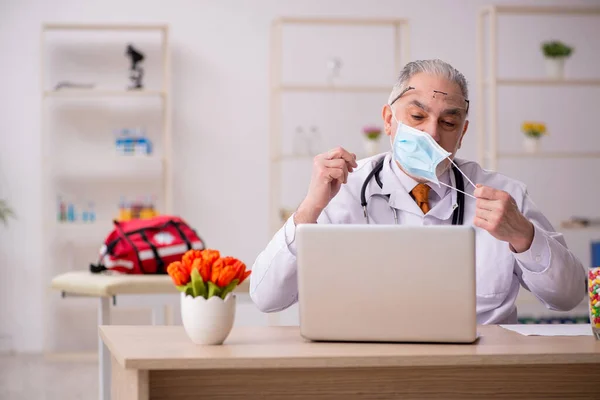 Yaşlı erkek doktor salgın sırasında klinikte çalışıyor. — Stok fotoğraf