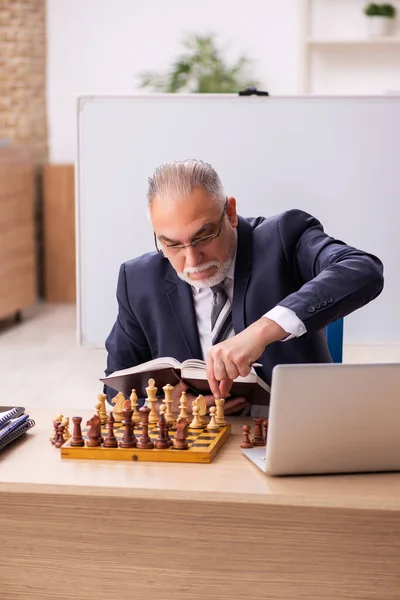 Velho empregado masculino jogando xadrez no local de trabalho — Fotografia de Stock