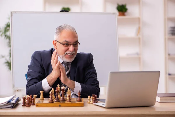 Velho empregado masculino jogando xadrez no local de trabalho — Fotografia de Stock