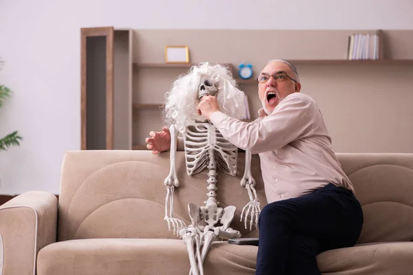 Staruszek siedzi na kanapie z żeńskim szkieletem — Zdjęcie stockowe