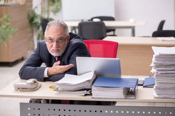 Überalterte männliche Mitarbeiter und zu viel Arbeit am Arbeitsplatz — Stockfoto