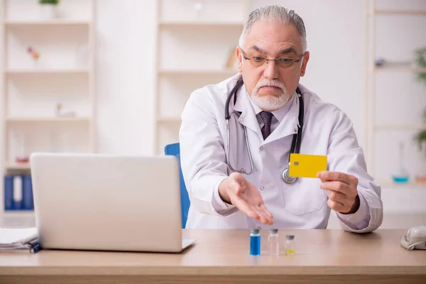 Kredi kartı ödemesi ve aşı konseptinde yaşlı bir erkek doktor. — Stok fotoğraf