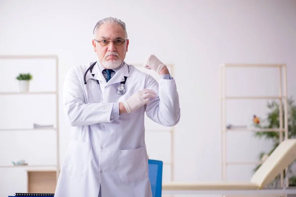 Gammal manlig läkare som arbetar på kliniken — Stockfoto