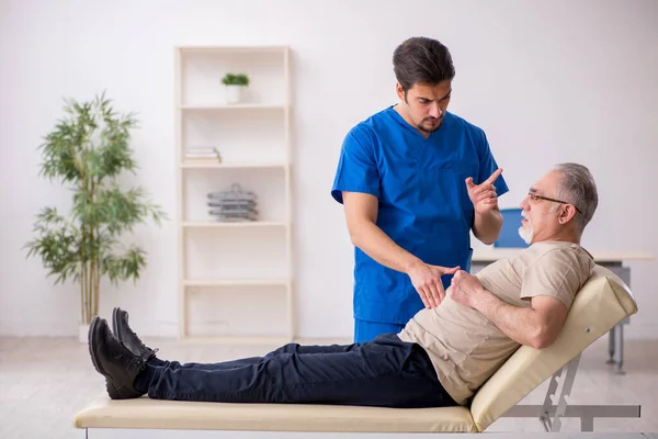 Old male patient visting young male doctor — Stock Photo, Image