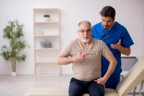 Vecchio paziente maschio visting giovane medico maschio — Foto Stock