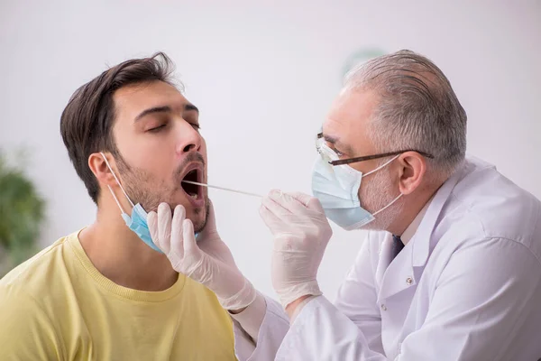 Paciente masculino joven que visita a un viejo médico otorrinolaringologis —  Fotos de Stock