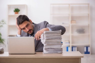 Ofisteki aşırı işten memnun olmayan genç bir erkek işçi.