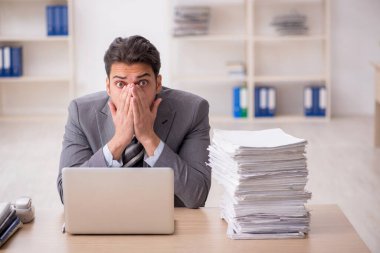 Ofisteki aşırı işten memnun olmayan genç bir erkek işçi.