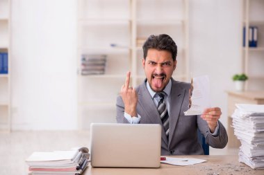 Ofisteki aşırı işten memnun olmayan genç bir erkek işçi.