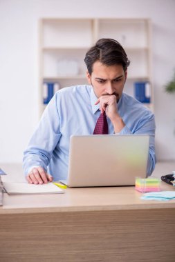 Genç bir erkek çalışan ve ofiste çok fazla iş var.