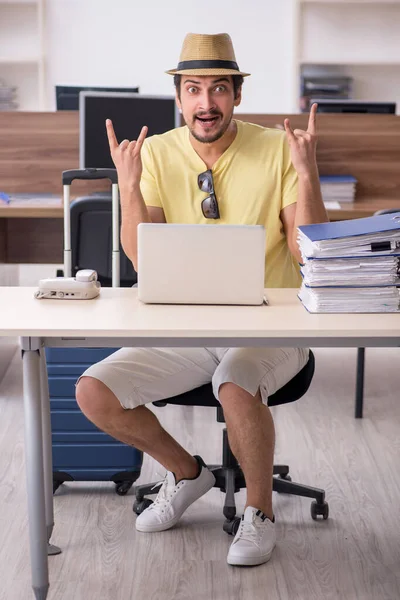 Joven empleado masculino preparándose para el viaje en el lugar de trabajo — Foto de Stock